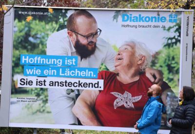 Diakonie-Direktorin Maria Katharina Moser und Majed Kabbani vor dem Plakat der neuen Kampagne. (Foto: epd/M. Uschmann)