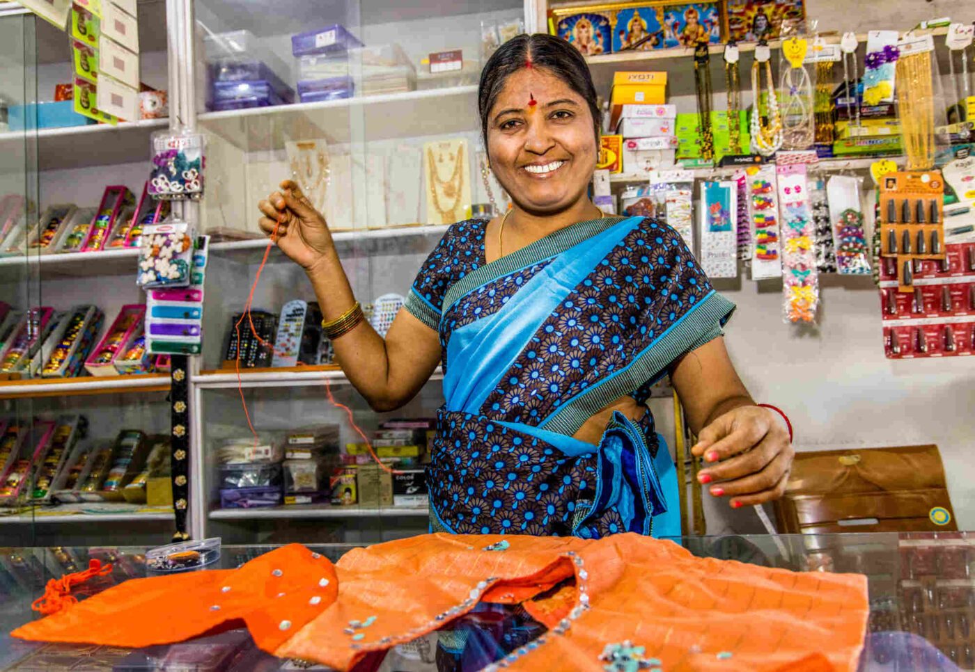 Pittala Rama Rani, Kundin des Oikocredit-Partners Vreedhi Financial Services in Indien, bringt Schmuck an einem Kleidungsstück an, das sie in ihrem Geschäft schneidert. (Foto: Opmeer Reports)